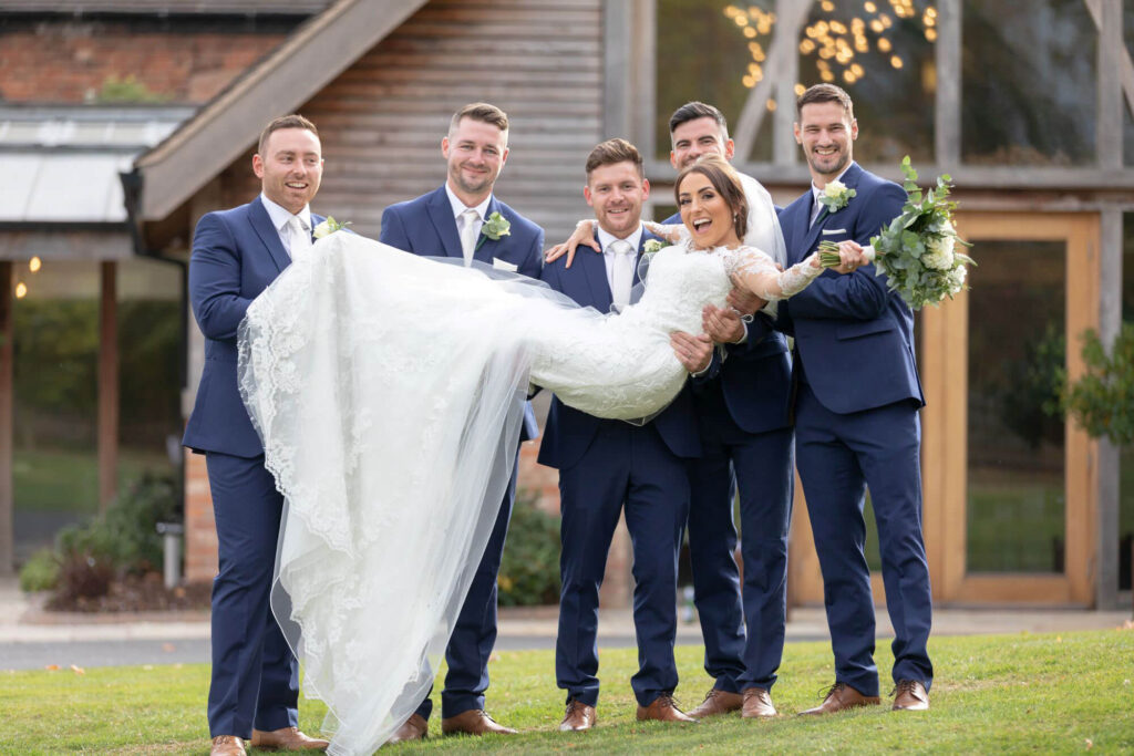 bride white dress flowers bouquet lifted by groom groomsmen reception mythe barn luxury venue leicestershire oxfordshire wedding photography 56
