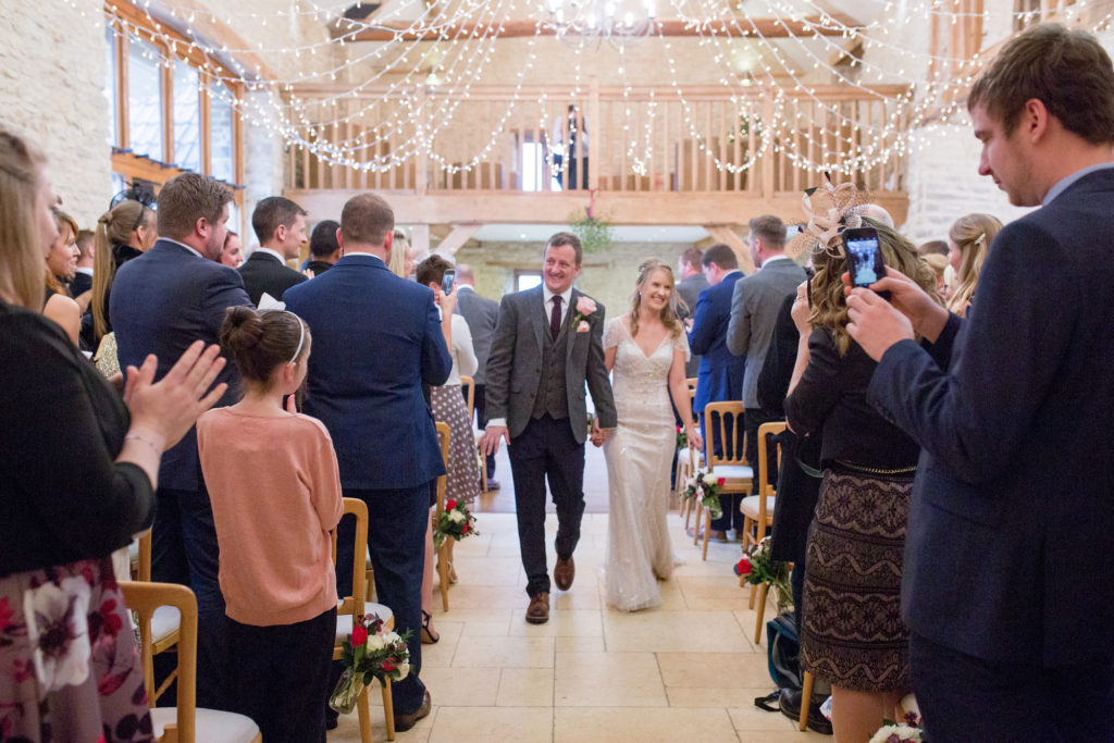 bride groom walk down aisle kingscote barn tetbury oxfordshire wedding photography