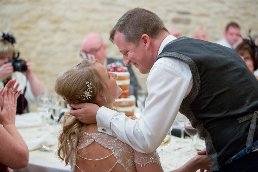 smiling groom leans to kiss bride kingscote barn tetbury oxford wedding photographer