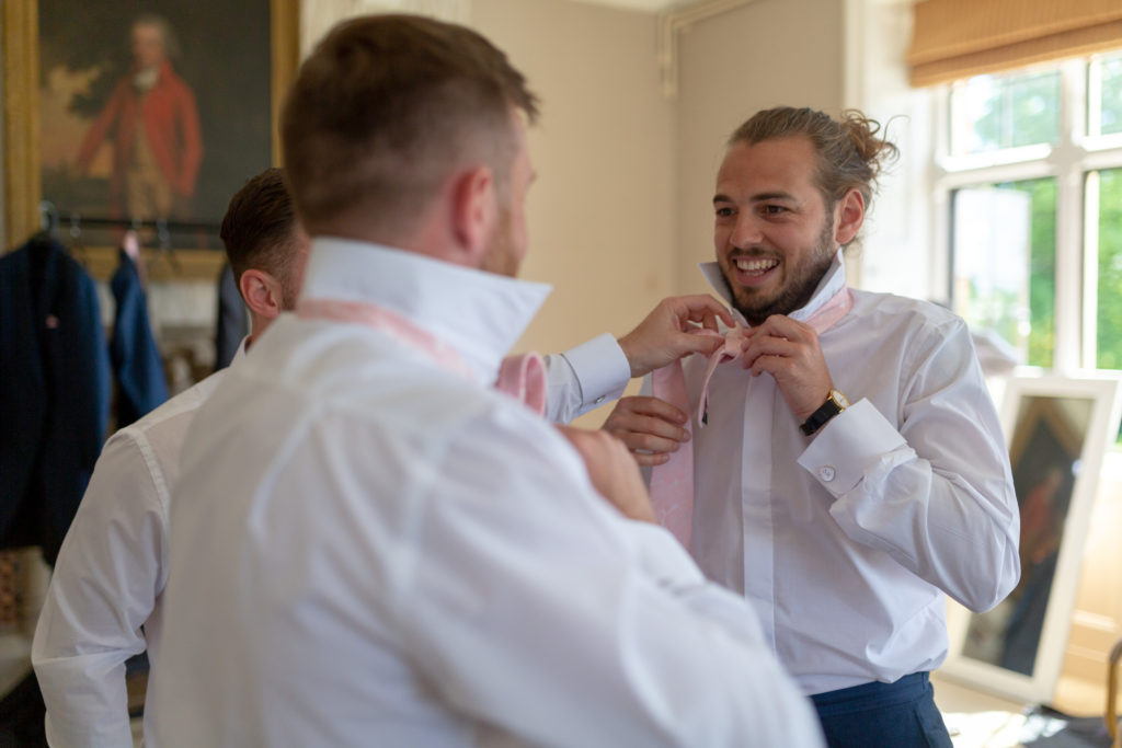 20 smiling groomsmen fix ties groom prep the elvetham hartley wintney hampshire oxford wedding photographers