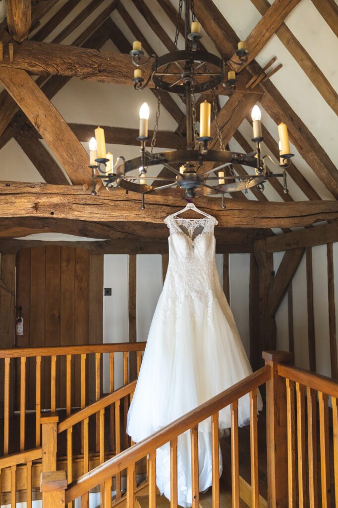 brides gown hangs above cain manor staircase surrey hampshire borders oxford wedding photographers