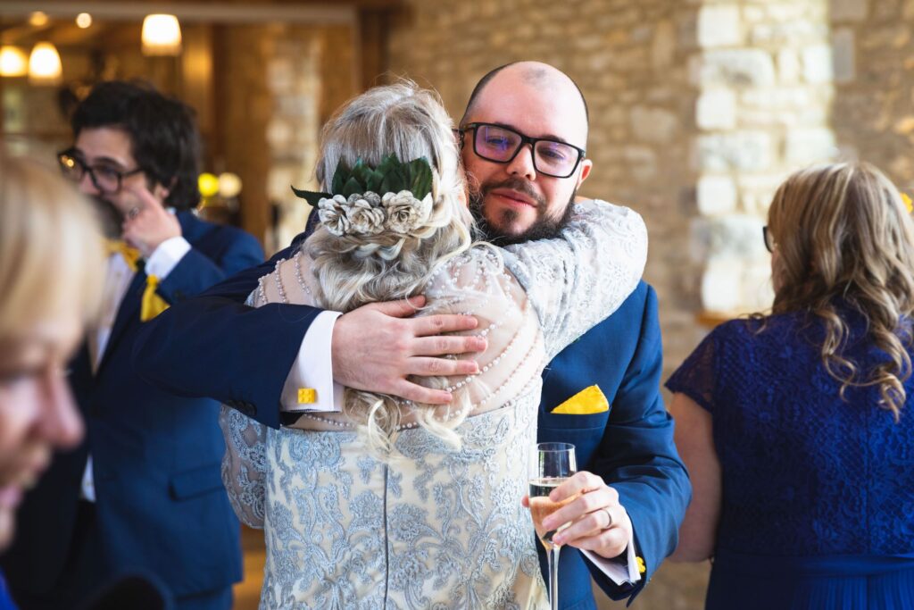 groom hugs new mother in law champagne reception caswell house oxford wedding photographers