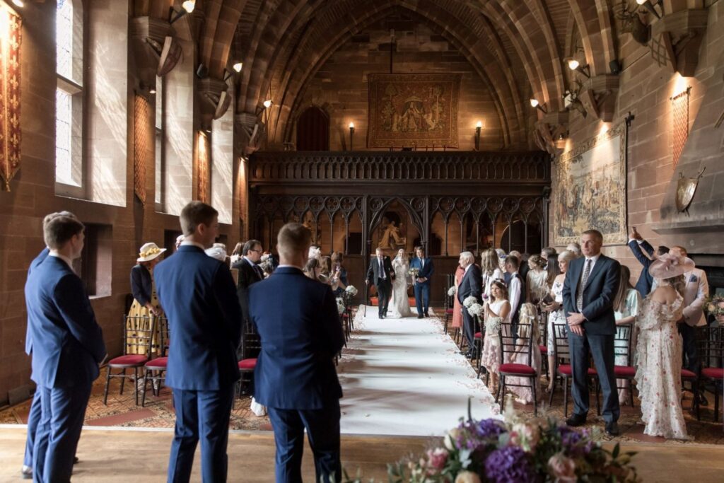 001 bride escorted towards groom groomsmen peckforton castle ceremony cheshire oxford wedding photographer