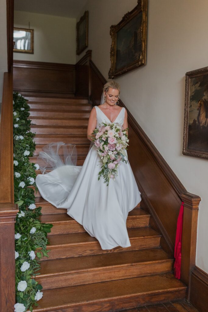 bride descends staircase holdenby house oxford wedding photographers