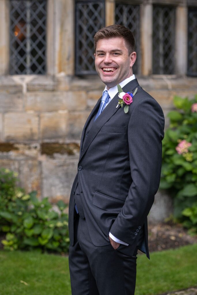 36 laughing groom with lapel corsage smallfield place garden surrey oxfordshire wedding photographer
