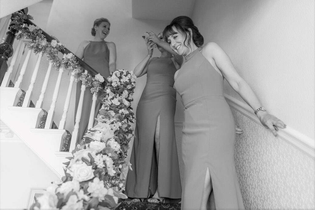 21 smiling bridesmaids descend stairs london bridal prep oxford wedding photographers