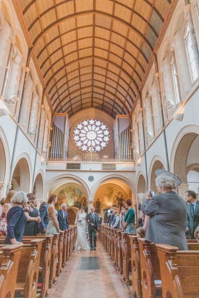 34 guests watch bridal party walk down aisle oxford oratory s r urwin photographer oxfordshire