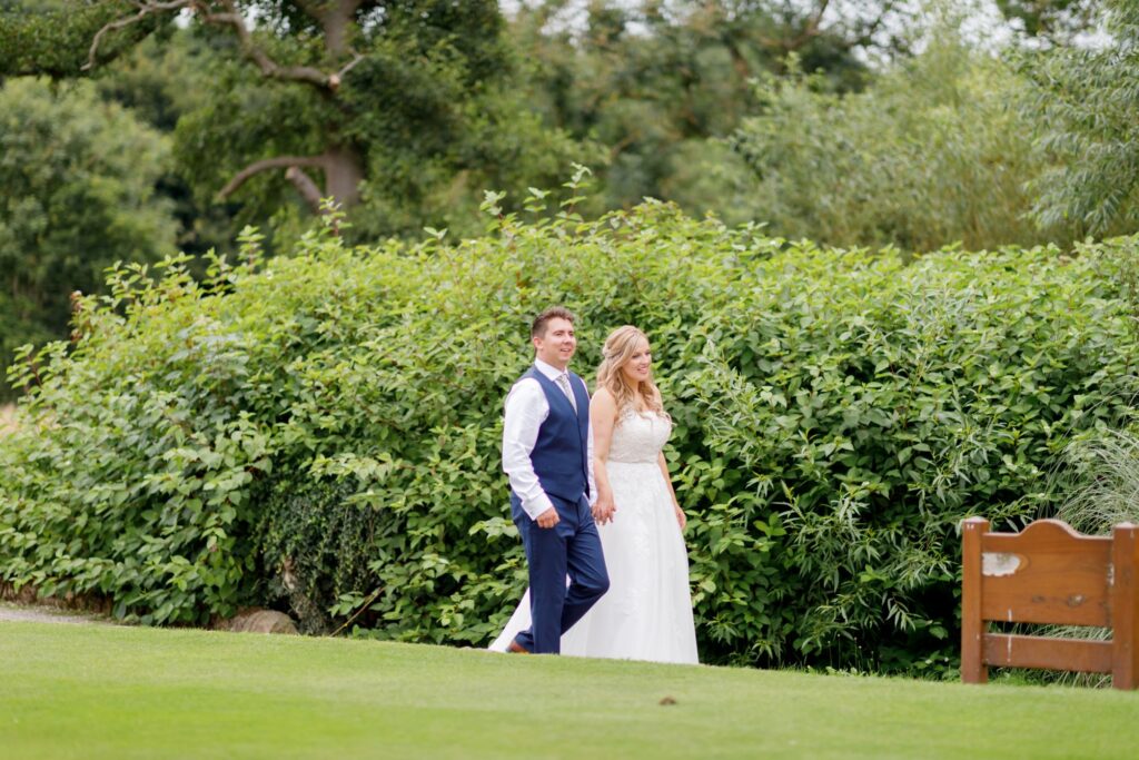 87 bride groom stroll handing hands horsley lodge golf club grounds derbyshire oxfordshire wedding photographer