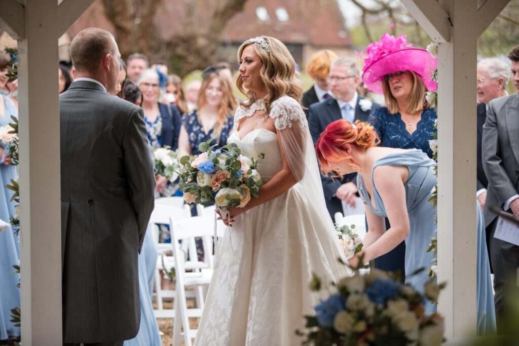 61 bridesmaid adjusts brides train outdoor ceremony ihg hotel sandford oxford oxfordshire wedding photographers