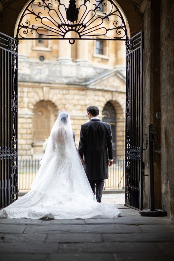22 bride groom walk through gated arch radcliffe camera oxford oxfordshire wedding photographer