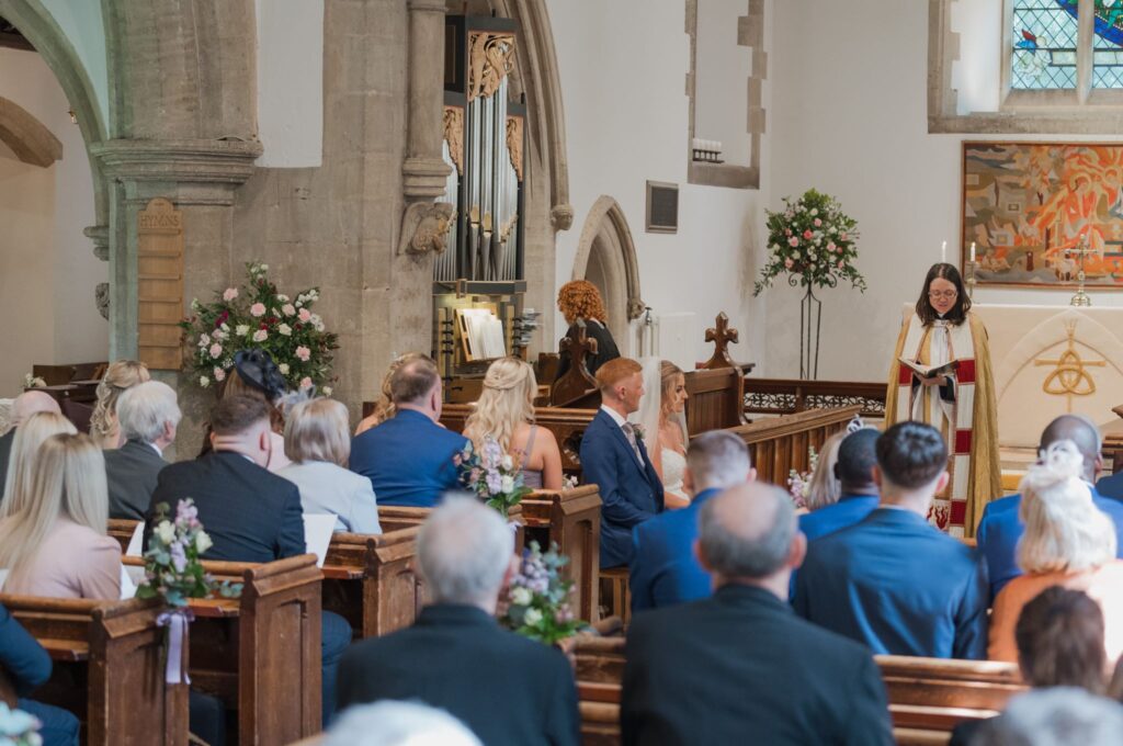 50 seated bride groom hear priest headington quarry parish church oxford oxfordshire wedding photographers