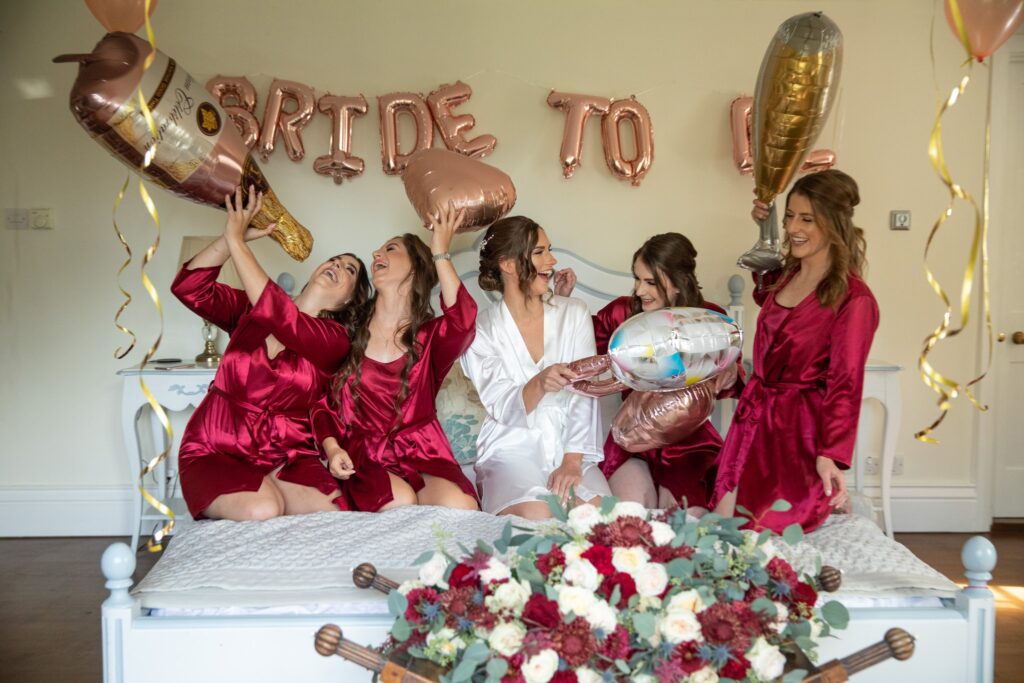 04 bride bridesmaids hold blowup balloons bridal prep the great tythe barn tetbury gloucestershire oxford wedding photography