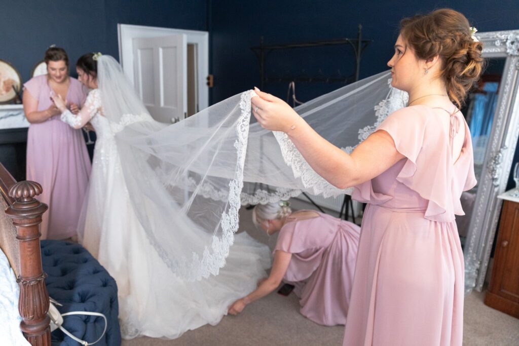 52 bridesmaid holds brides gown train bridal prep prestwold hall loughborough oxfordshire wedding photographers