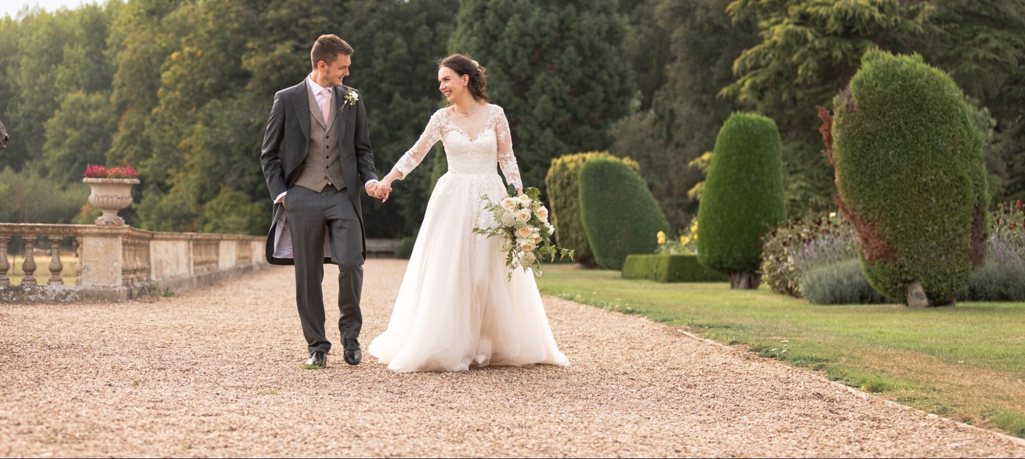smiling bride holds grooms hand prestwold hall garden path leicestershire oxfordshire wedding photographers