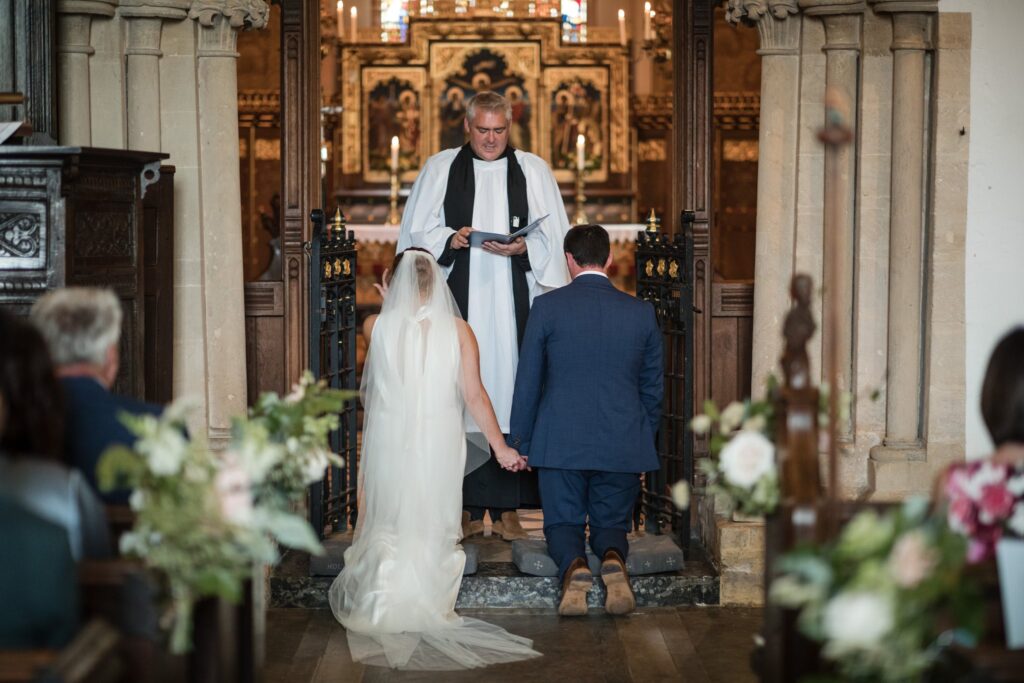 43 bride groom kneel before priest holy trinity church ardington wantage oxfordshire oxford wedding photographers