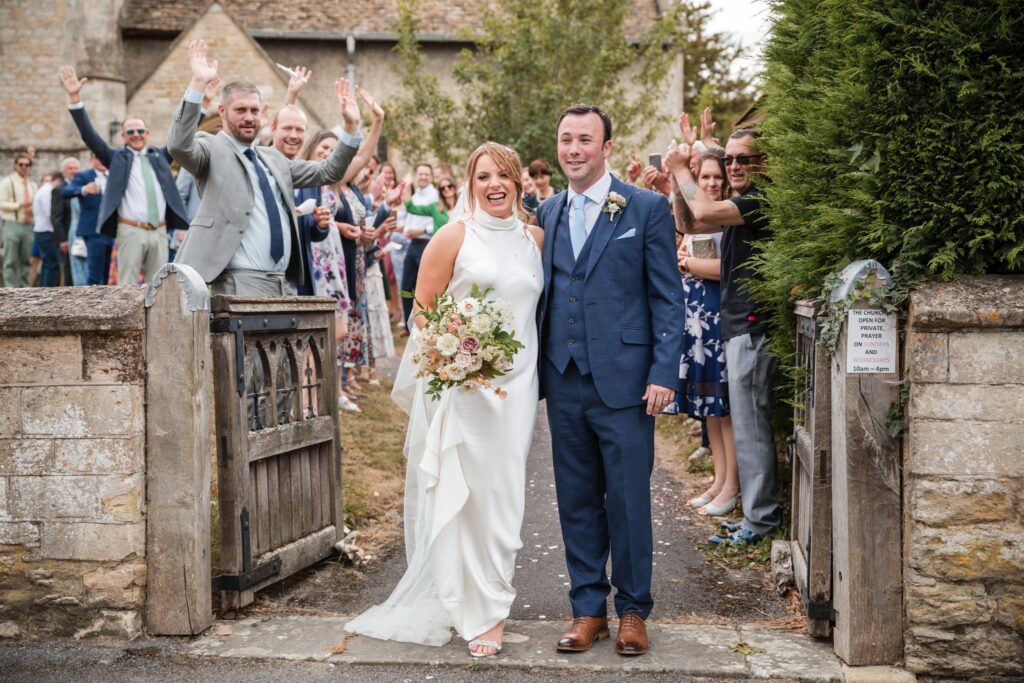 52 bride groom waving guests holy trinity churchyard ardington wantage oxfordshire wedding photographers