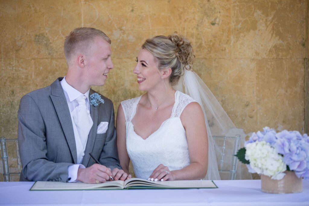 smiling bride groom sign marriage register stowe house buckinghamshire oxfordshire wedding photography